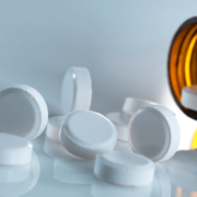the-real-cbd-blog-can-you-take-cbd-with-painkillers Hvide tabletter falder ud af væltet glas