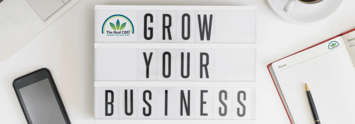 GROW YOUR BUSINESS-skilt på kontorbord med kaffe, mobiltelefon og notesbog