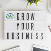 The-Real-CBD-Blog-CBD-CBD-GROSSIST-VS.-PRIVATE-LABEL-CBD-VS.-CBD-DROP-SHIPPING-VS.-CBD-AFFILIATE GROW YOUR BUSINESS-skilt på kontorbord med kaffe, mobiltelefon og notesbog
