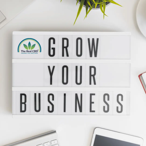 GROW YOUR BUSINESS-skilt på kontorbord med kaffe, mobiltelefon og notesbog