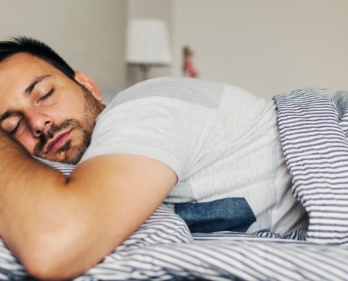 Mand sover trygt på maven i en frisk seng
