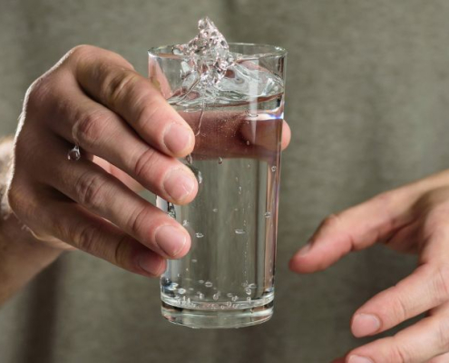 Mand holder et glas vand med rystende hænder