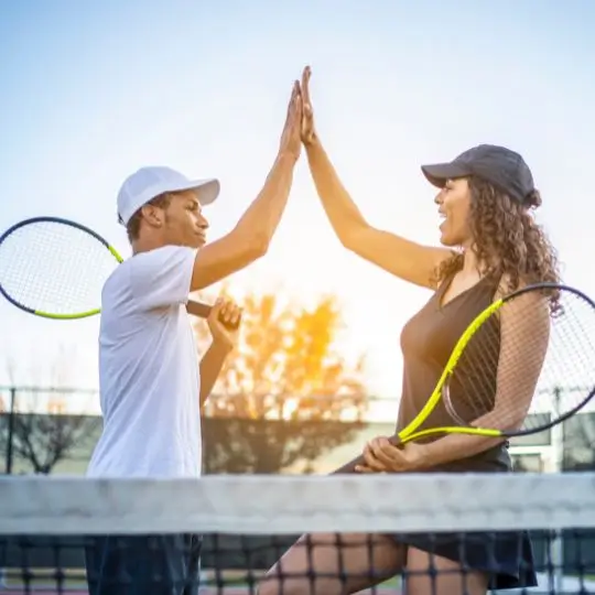 To tennisspillere giver high-five på en tennisbane