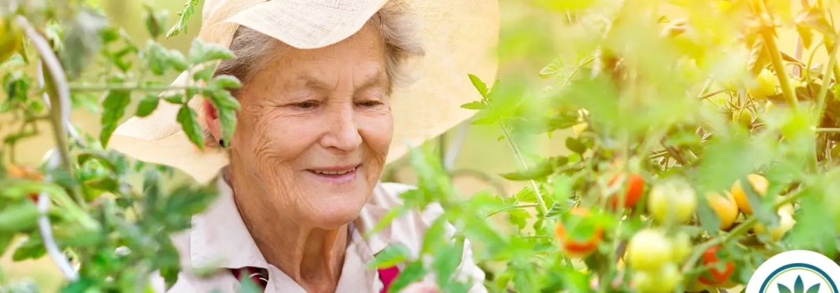 Glad kvinde med sommerhat står mellem en masse blomster