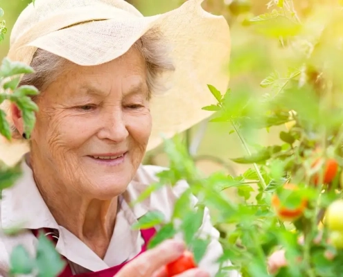 Glad kvinde med sommerhat står mellem en masse blomster