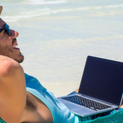 the-real-cbd-blog-cbd-til-digitale-nomader En mand ligger i en hængekøje på stranden med sin bærbare computer på skødet.