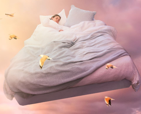 Kvinde sover i en stor seng som svæver rundt i himlen