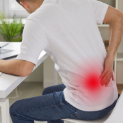 the-real-cbd-blog-CBD+til-thoracix-rygsmerter-ved-kontorarbejde Mand sidder ved sit kontorbord og holder sig for ryggen i smerte