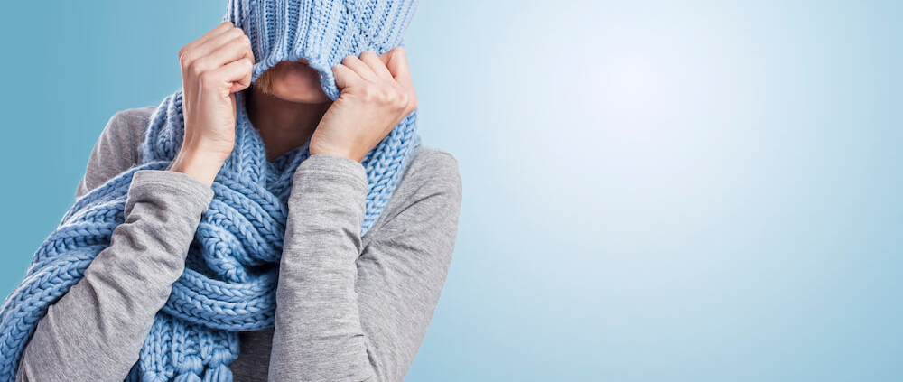 Mujer tirando de un gorro azul de punto sobre su cabeza