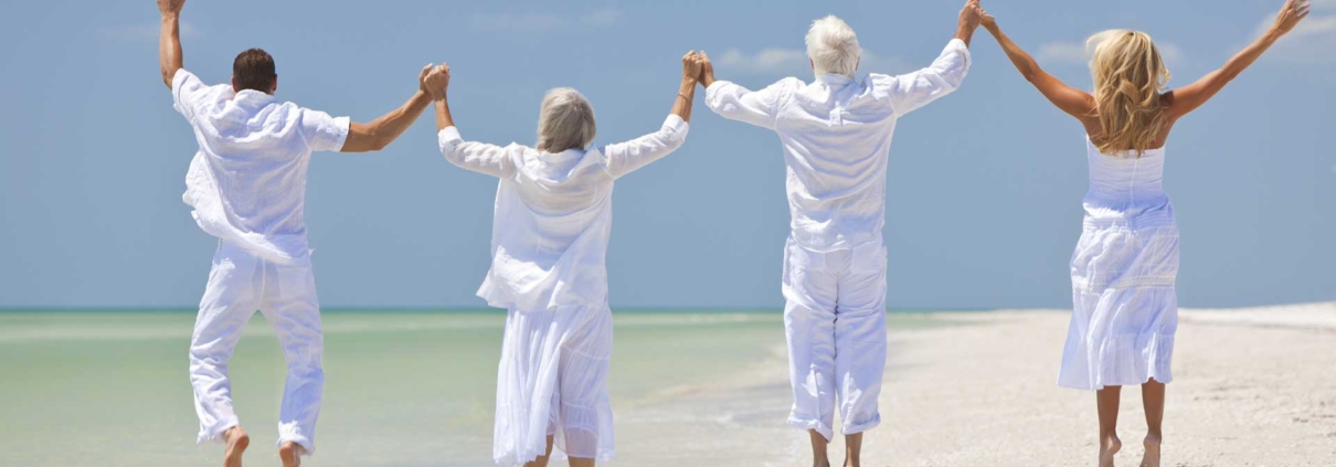4 personas felices vestidas de blanco saltando en una playa exótica