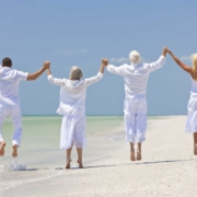4 personas felices vestidas de blanco saltando en una playa exótica