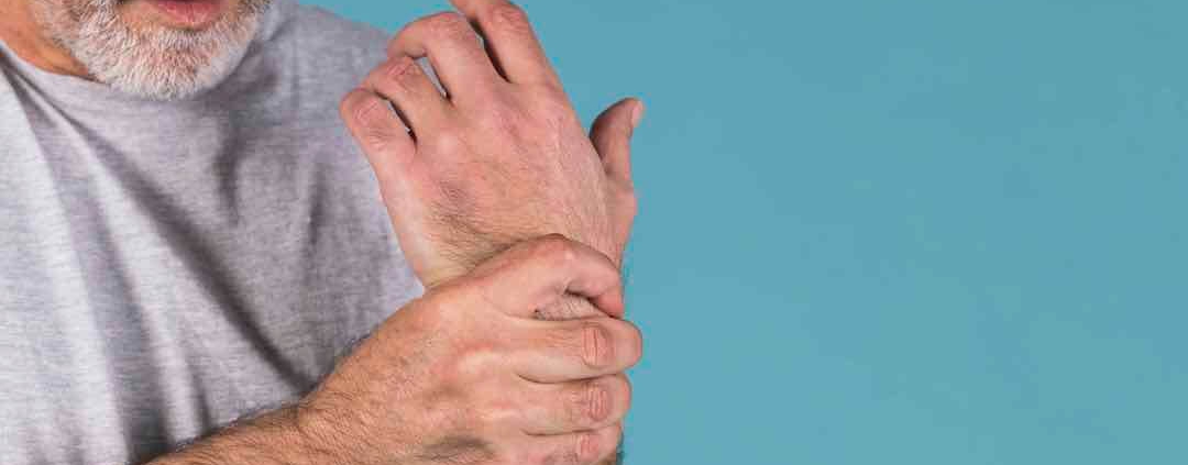 Anciano sujetándose la muñeca con dolor