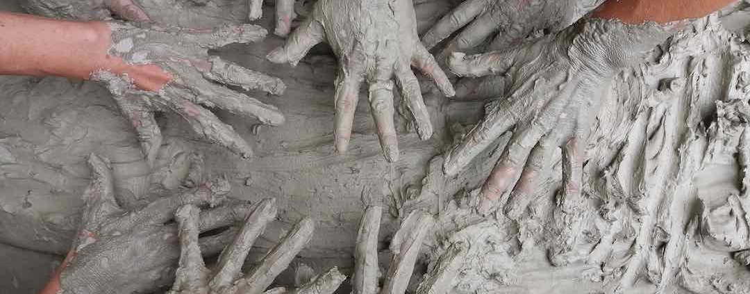 10 manos embarradas en un montón de barro
