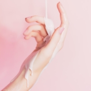 Mano de mujer con crema corriendo por su brazo