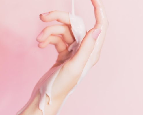Mano de mujer con crema corriendo por su brazo