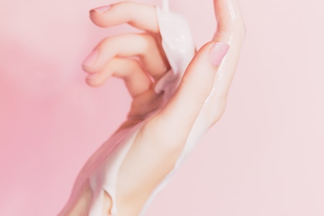 Mano de mujer con crema corriendo por su brazo