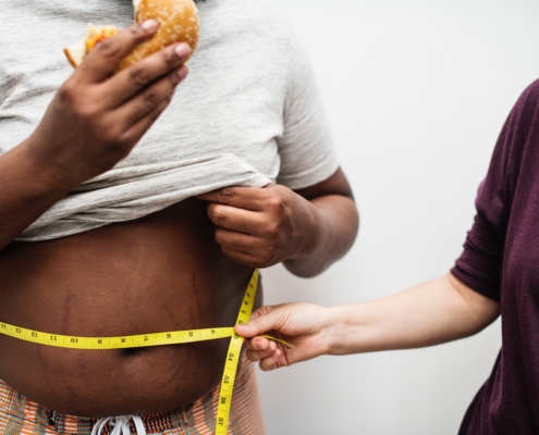 A un hombre con una hamburguesa en la mano le miden la cintura