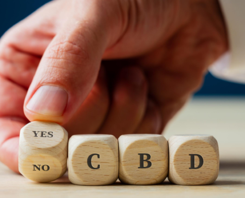 Hombre girando dados SÍ/NO delante de dados que deletrean CBD