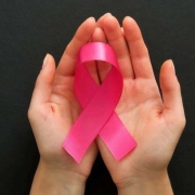 Manos femeninas sosteniendo un lazo rosa contra el cáncer