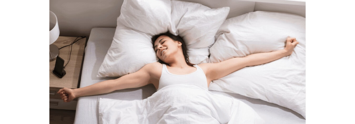Mujer despertando feliz en cama blanca