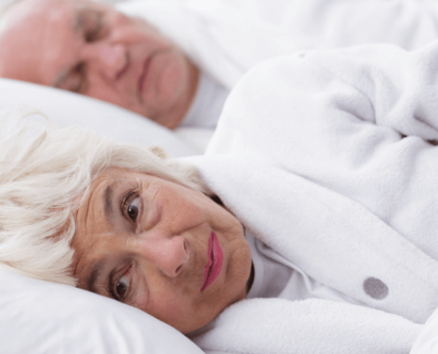 Una pareja de ancianos en la cama. Uno durmiendo, otro despierto