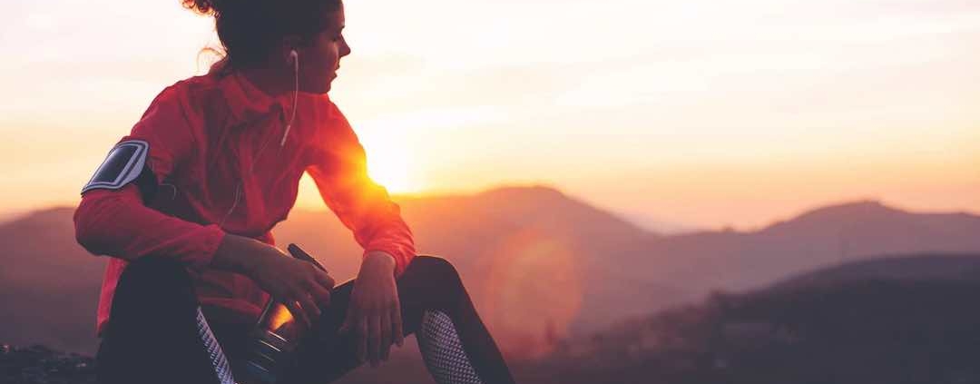 Mujer en la cima de una montaña sentada después de correr