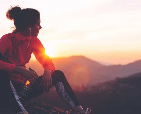 Mujer en la cima de una montaña sentada después de correr