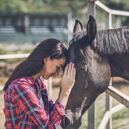 Mujer apoyada en su caballo