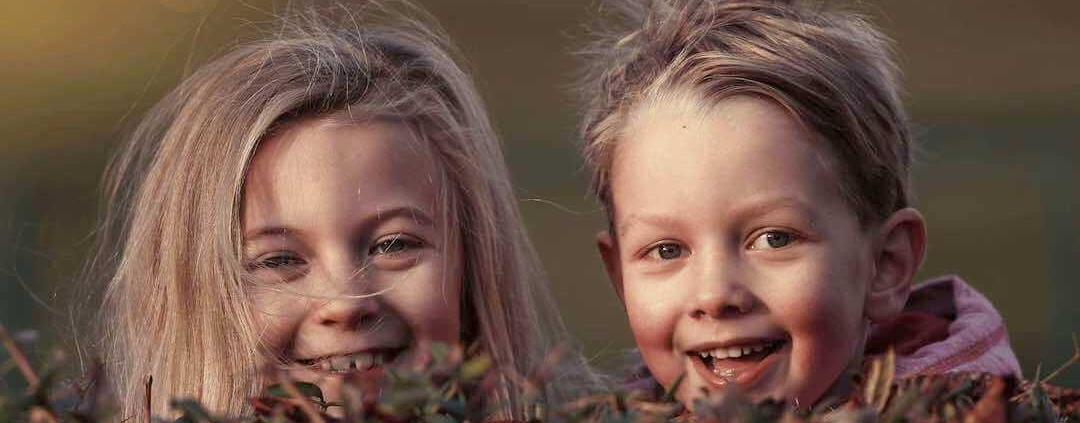Niños descarados asomándose por encima de un seto