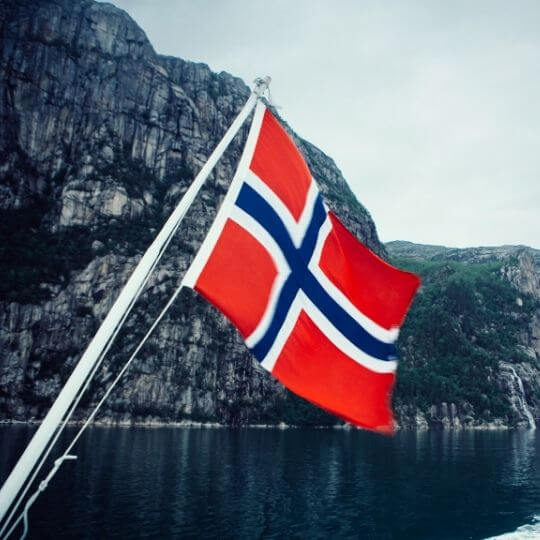Bandera noruega en un barco en un fiordo