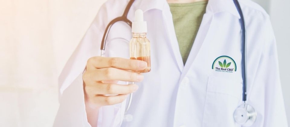 Médico con una botella de aceite en la mano