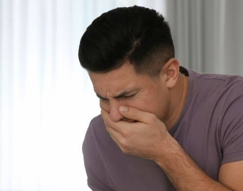 Hombre sujetándose la boca a punto de vomitar