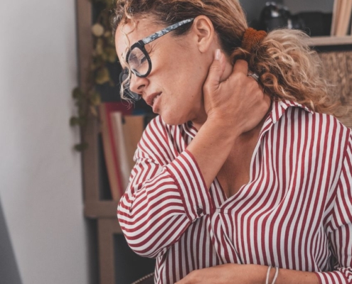Mujer sujetándose el cuello por el dolor