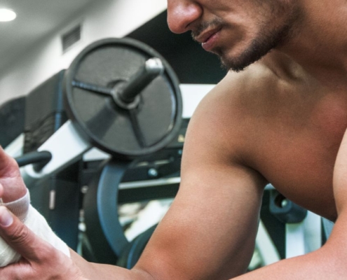Hombre musculoso en el gimnasio con la muñeca vendada