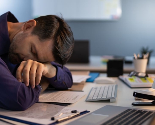 Hombre durmiendo en un despacho junto a sus ordenadores