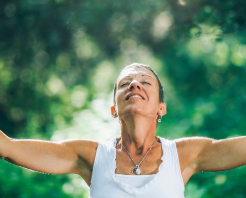 Mujer en el bosque con los brazos abiertos