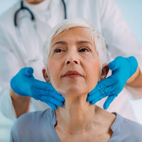 Médico examinando la tiroides de una paciente