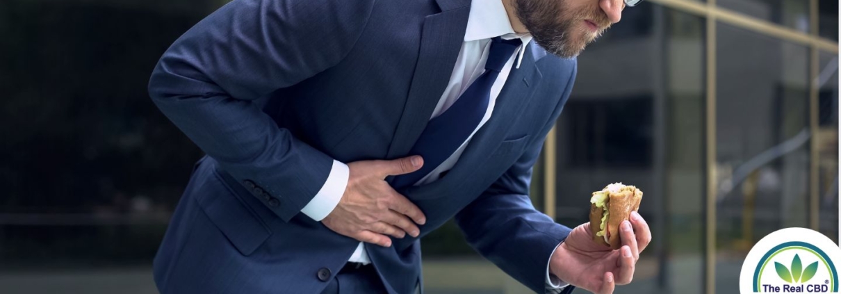 Hombre con dolor de estómago y un bocadillo en la mano