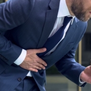 Hombre con dolor de estómago y un bocadillo en la mano