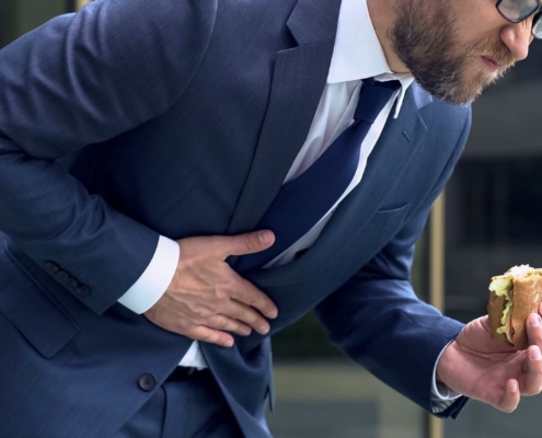 Hombre con dolor de estómago y un bocadillo en la mano