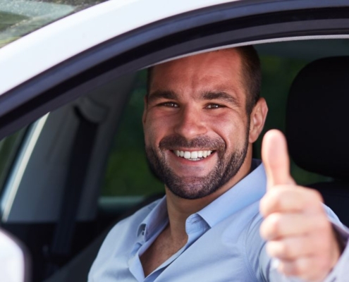Hombre levantando el pulgar en un coche
