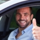 Hombre levantando el pulgar en un coche