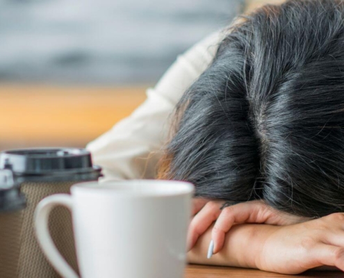 Mujer durmiendo delante de varias tazas de café