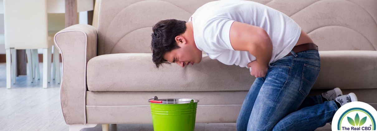 Hombre vomitando en un cubo verde