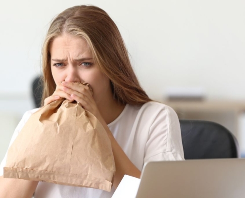 Mujer respirando en una bolsa de papel marrón