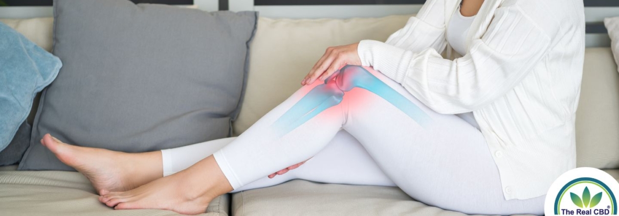 Mujer en el sofá sujetándose la rodilla por el dolor