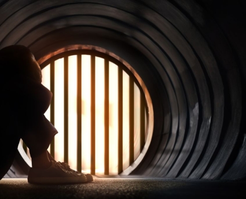 Niño sentado en un túnel con la cabeza apoyada en las rodillas