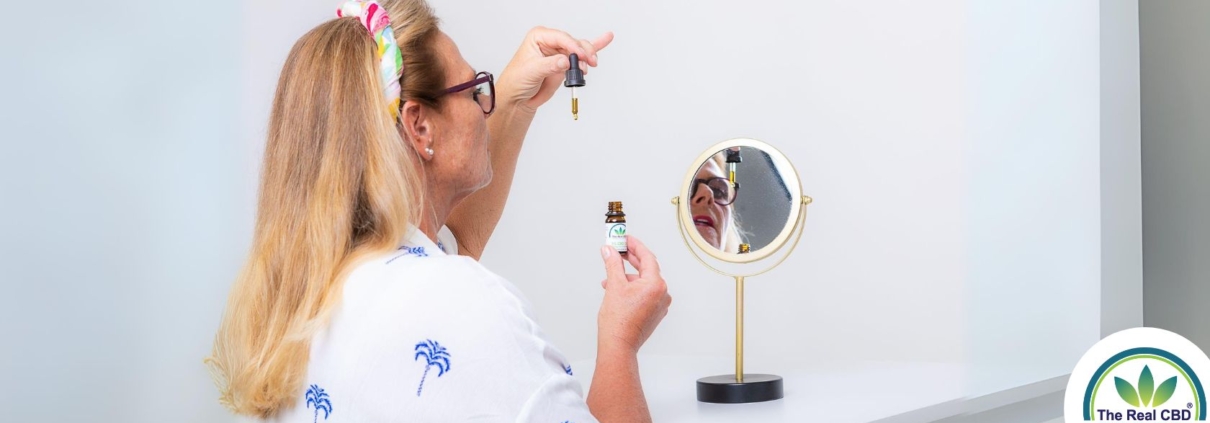 Mujer tomando aceite de CBD frente a un pequeño espejo