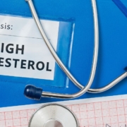 Informe médico sobre colesterol alto, pastillas y estetoscopio