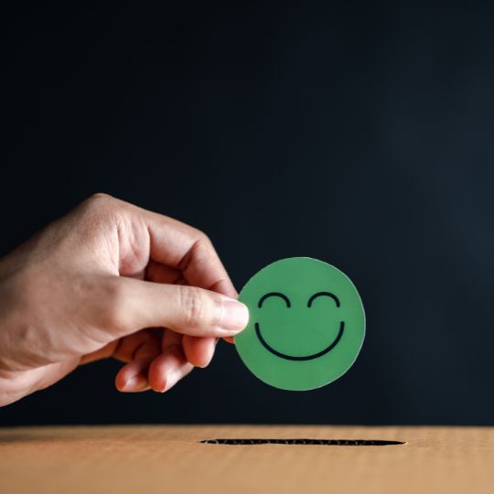 Mano que sostiene el círculo verde de una cara feliz
